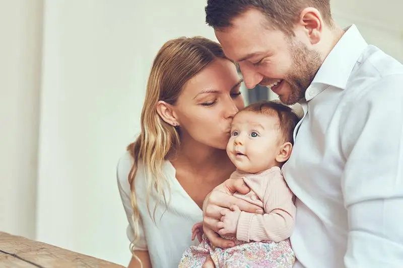 family-holding-and-kissing-baby